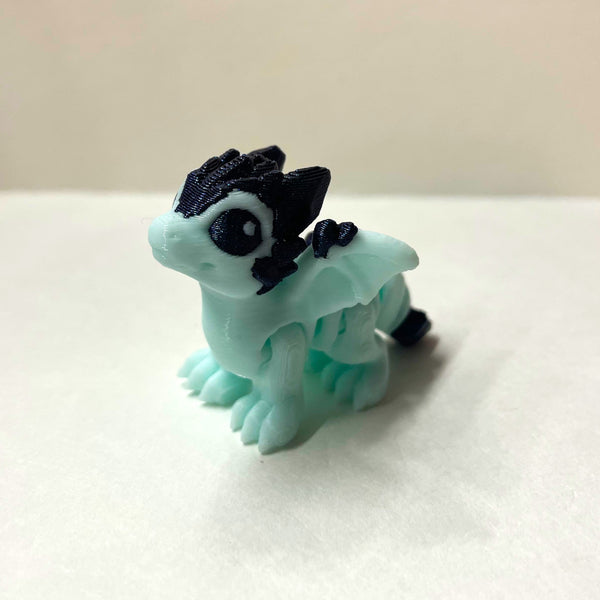 Small light blue dragon figurine with sparkly dark blue crystal accents on a white surface.